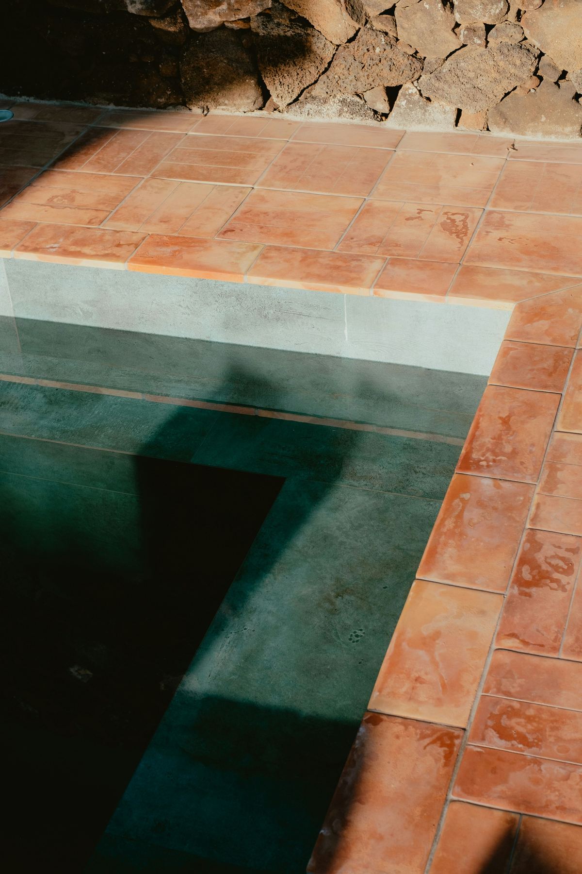 Close-up of terracotta-toned stone pool coping and steps