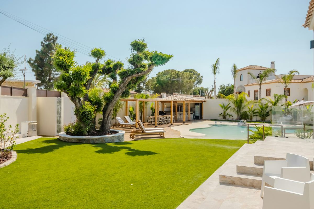 Mediterranean-style backyard with a pool, light stone decking, lawn and pergola